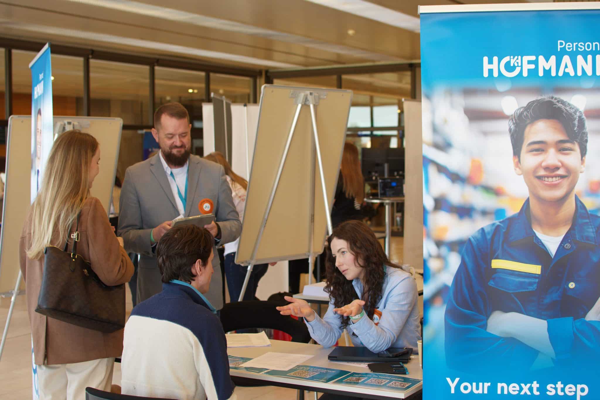 Visitors speaking with exhibitors at a Jobspin career fair